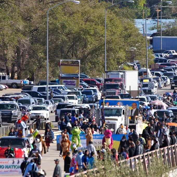 Heavy vehicle and pedestrian traffic arriving at a crowded outdoor event.
